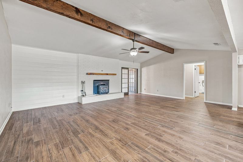 Living room with vaulted ceiling, exposed wood beam, and brick fireplace