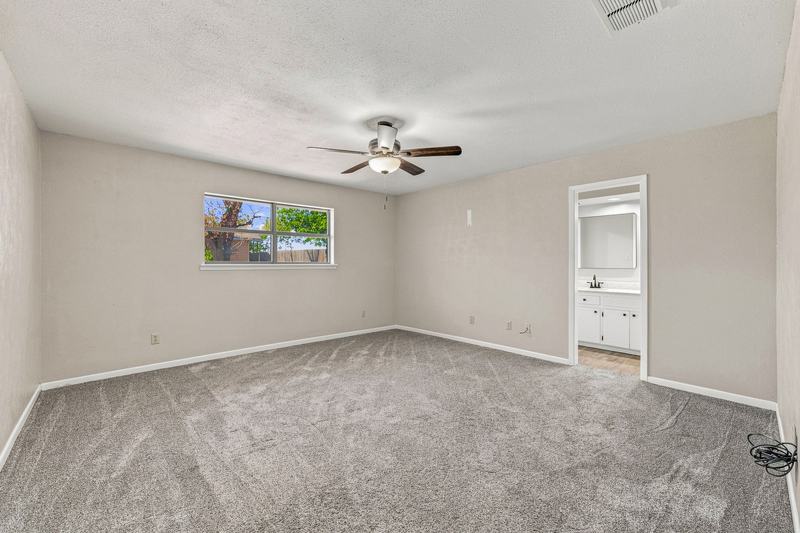 Carpeted bedroom with ceiling fan and an attached bathroom