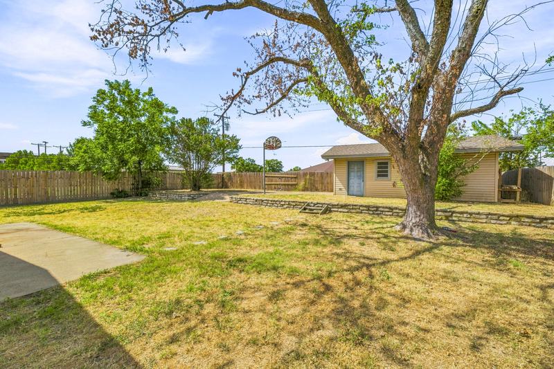 Fenced backyard with a large shade tree and the detached shop